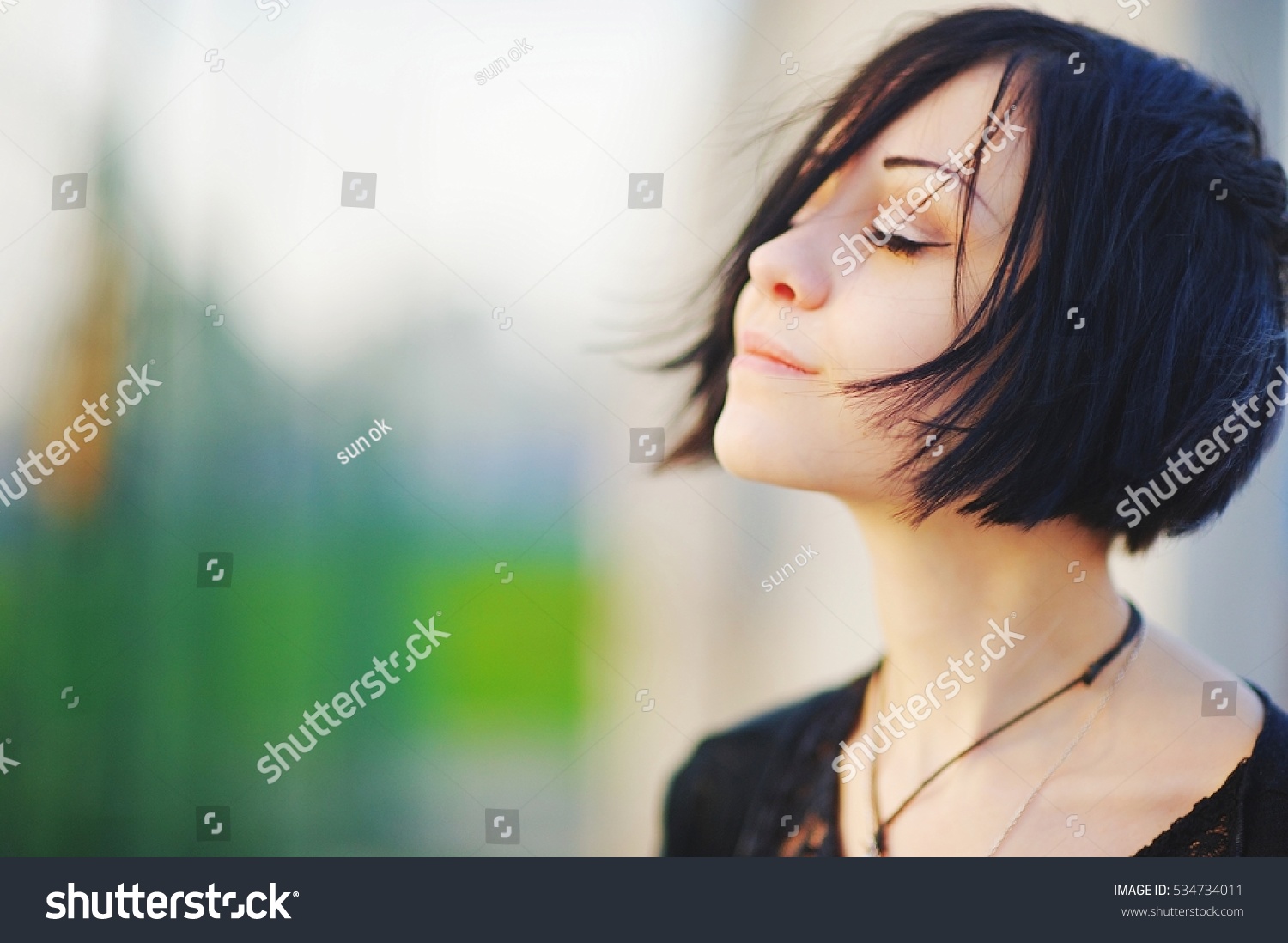 Young beautiful asian brunette woman, eyes closed, enjoying the bright warm day on blurred background close up. Air deep breath, yoga mind zen relax, calm peace pray hope concept. Light skin lady spa. #534734011
