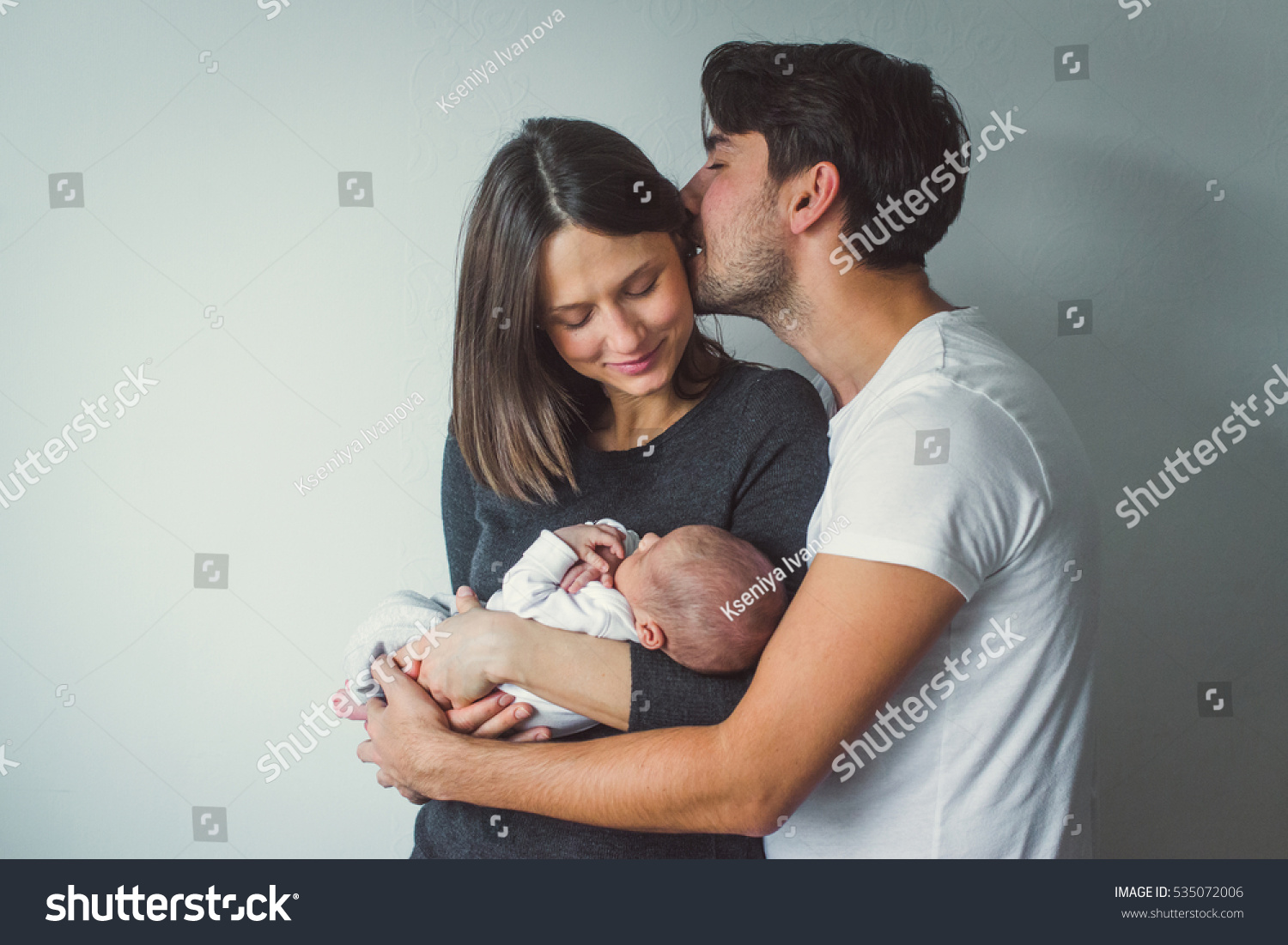 Woman and man holding a newborn.  A man kisses a woman. #535072006
