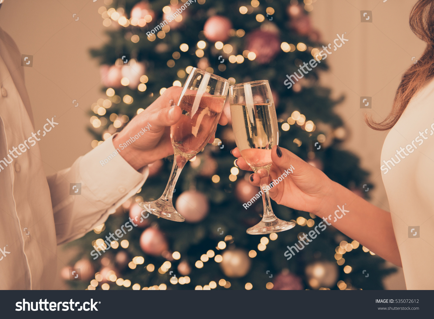 Cheers!Close up photo of two people holding glasses of shampagne on xmas #535072612