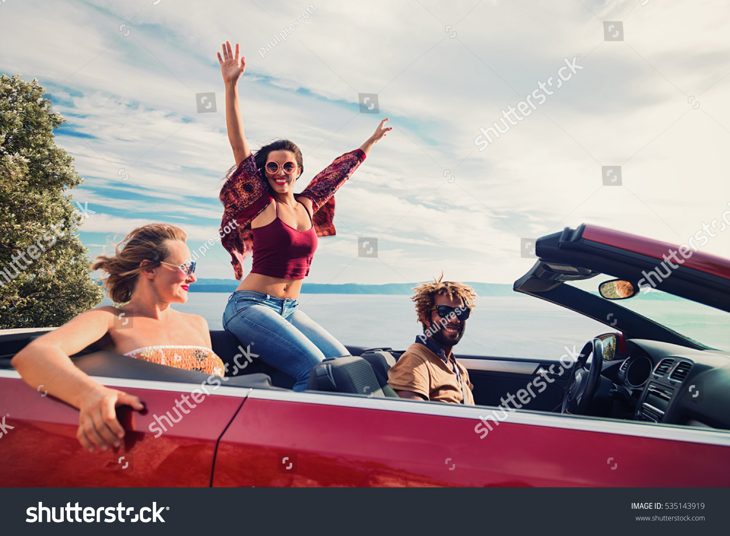 Group of happy young people in the red convertible. Vintage filter applied. #535143919