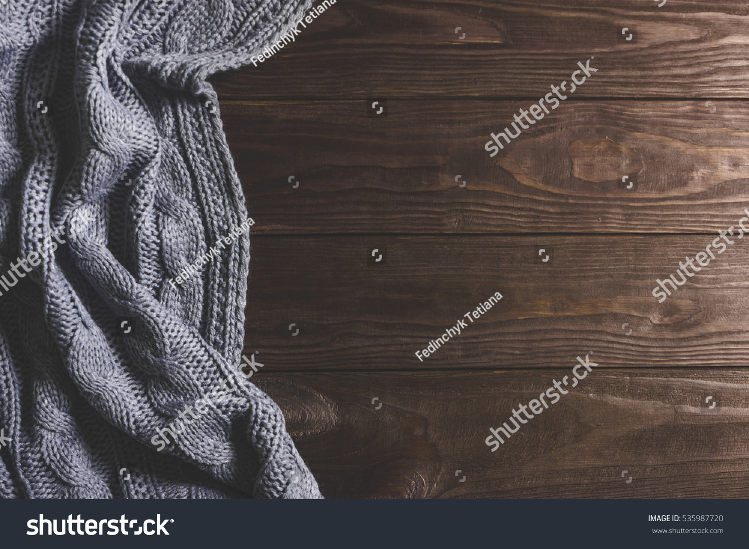 Warm Knitted crumpled gray blanket on a wooden background. Top view, space for text #535987720