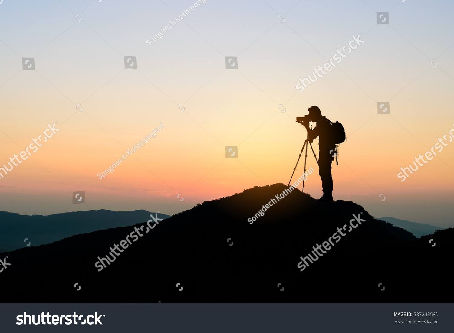 silhouette of photographer on top of mountain at sunset background #537243580
