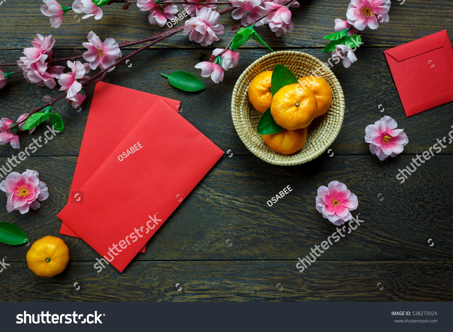 Top view accessories Chinese new year festival decorations.orange,leaf,wood basket,red packet,plum blossom on table wooden background with copy space. #538273924