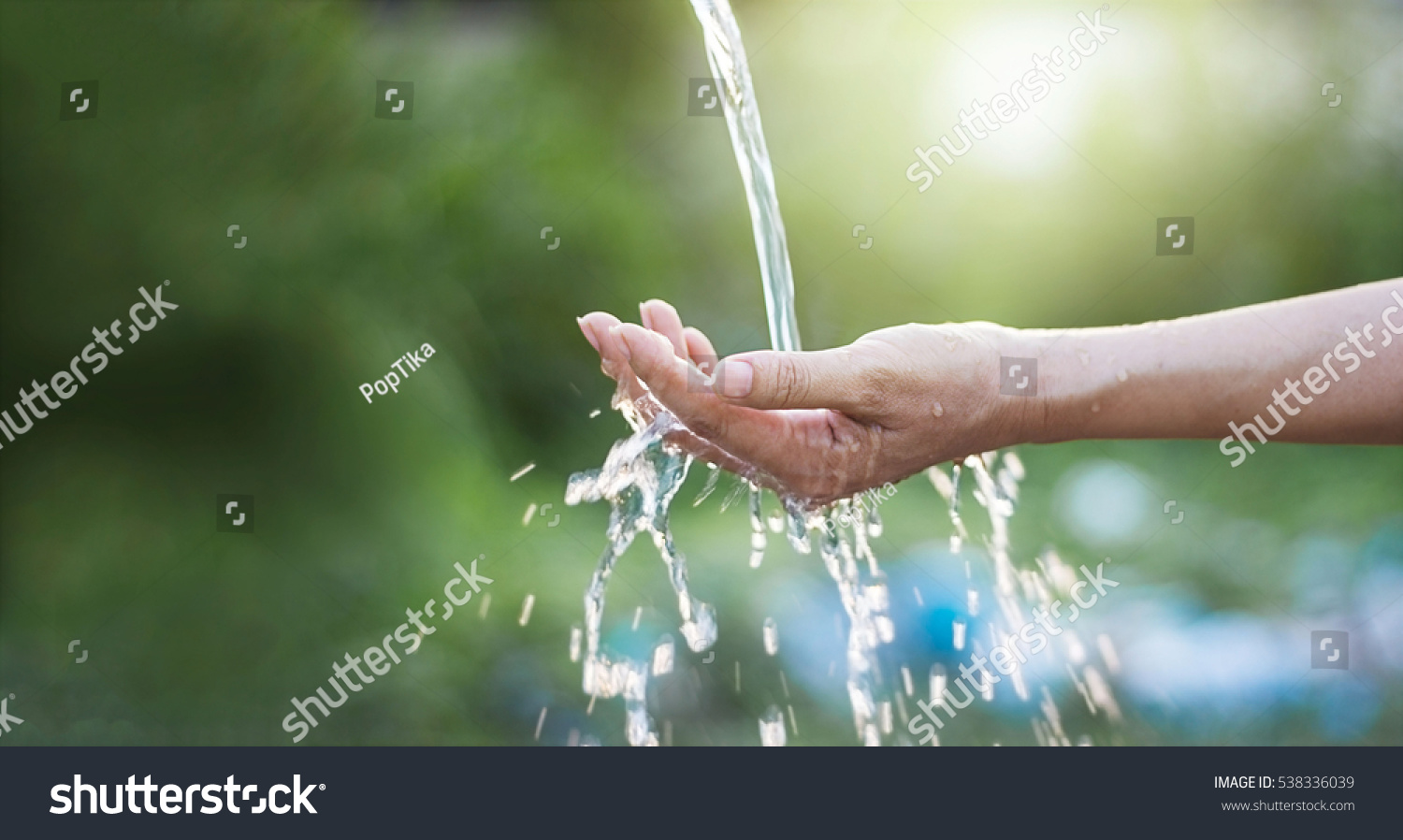 Water pouring in woman hand on nature background, environment issues

 #538336039