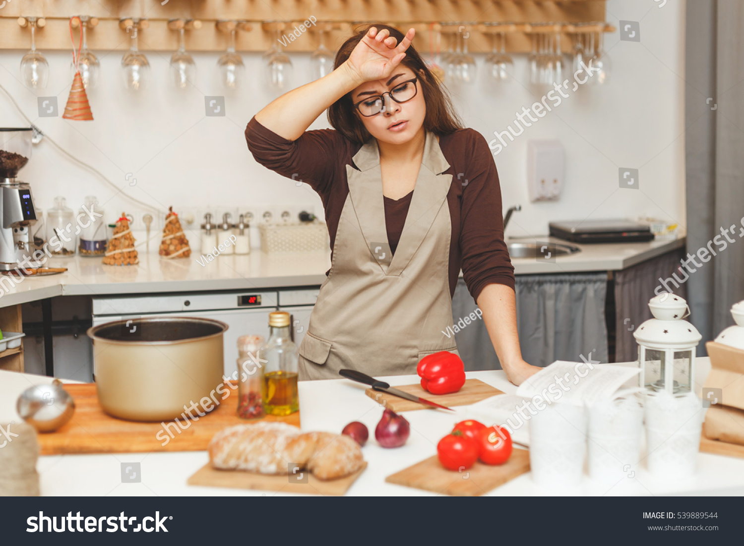 pretty young housewife in the kitchen is tired cooking tomato soup. #539889544