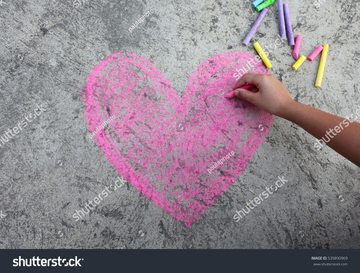  pink heart symbol is drawn on a sidewalk outside with chalk #539890969