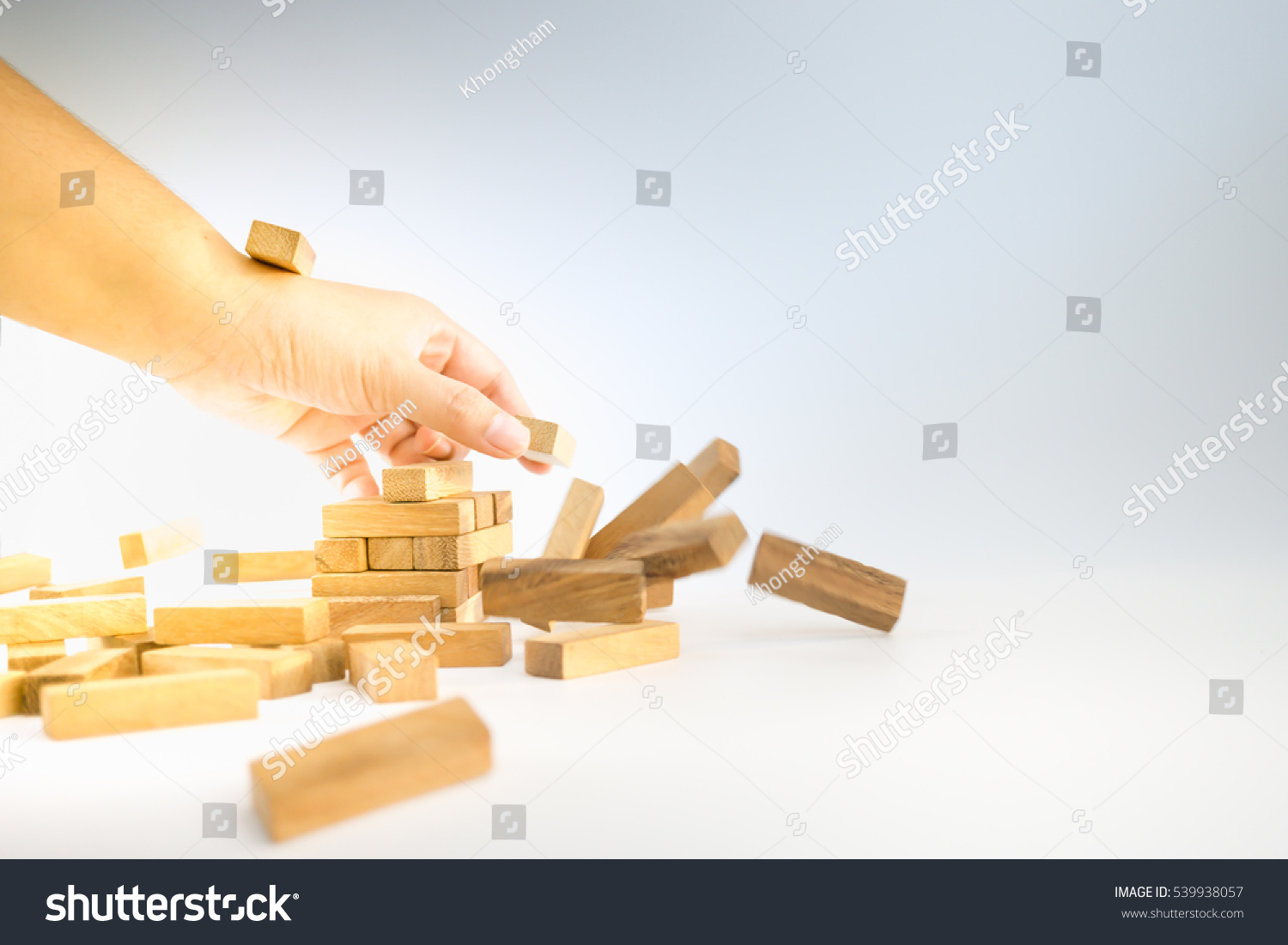 Hands of woman took  the brick and destroyed the wooden block tower. #539938057