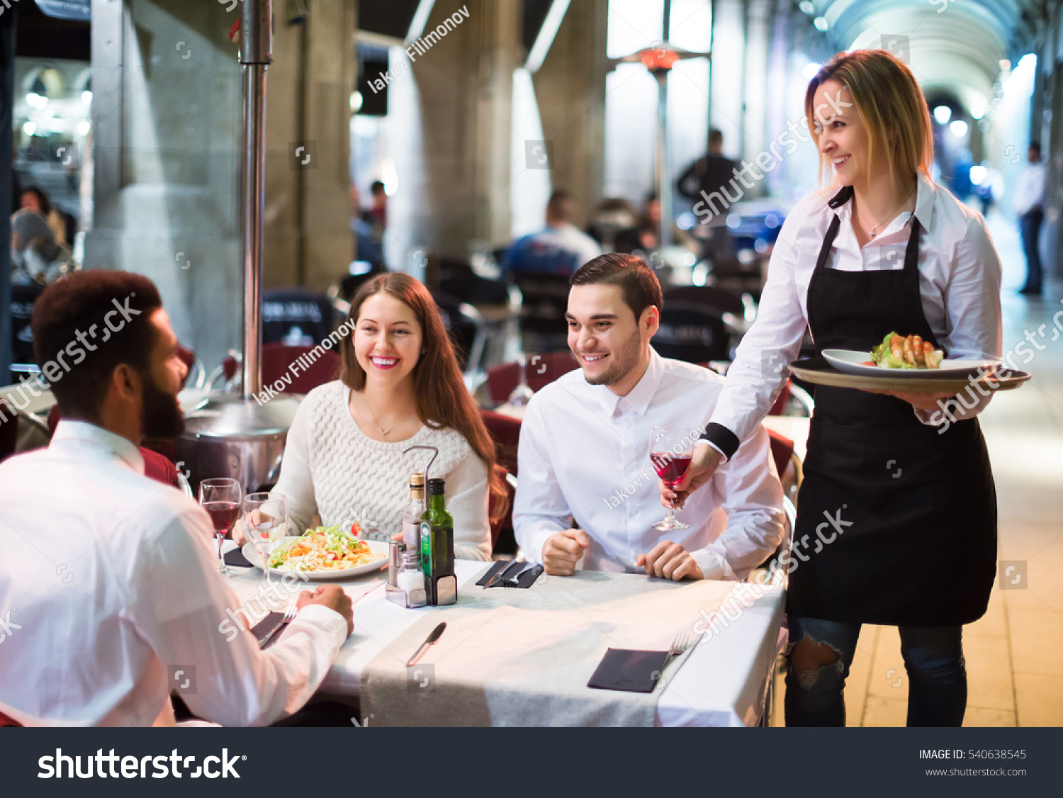 Portrait of smiling adult friends in outdoors restaurant and smiling waitress.  Focus on blonde girl #540638545