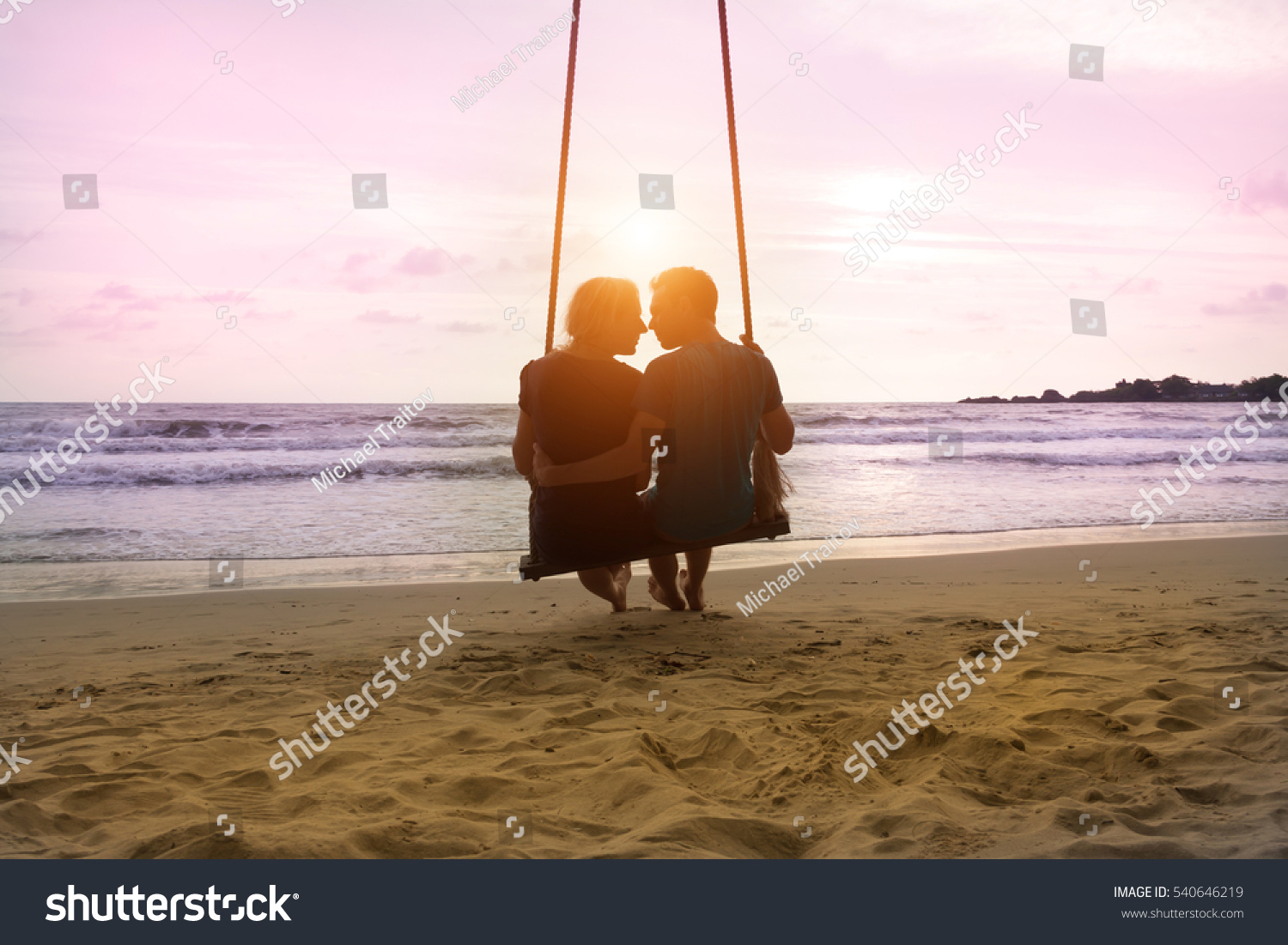 Romantic couple is sitting and kissing on sea beach on rope swing . Family vacation on honeymoon. Love and relationship #540646219