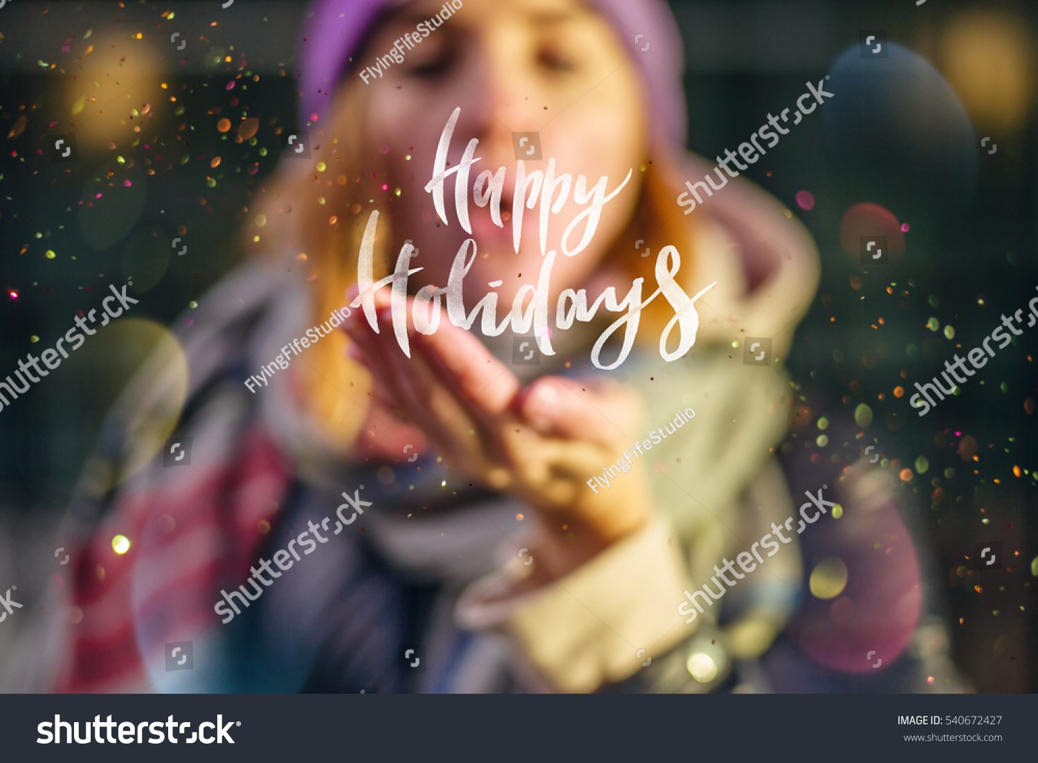 Young beautiful girl holding lettering "Happy Holidays", Young girl wearing at cozy scarf blowing a burst of magic glitter, Christmas magic time. #540672427