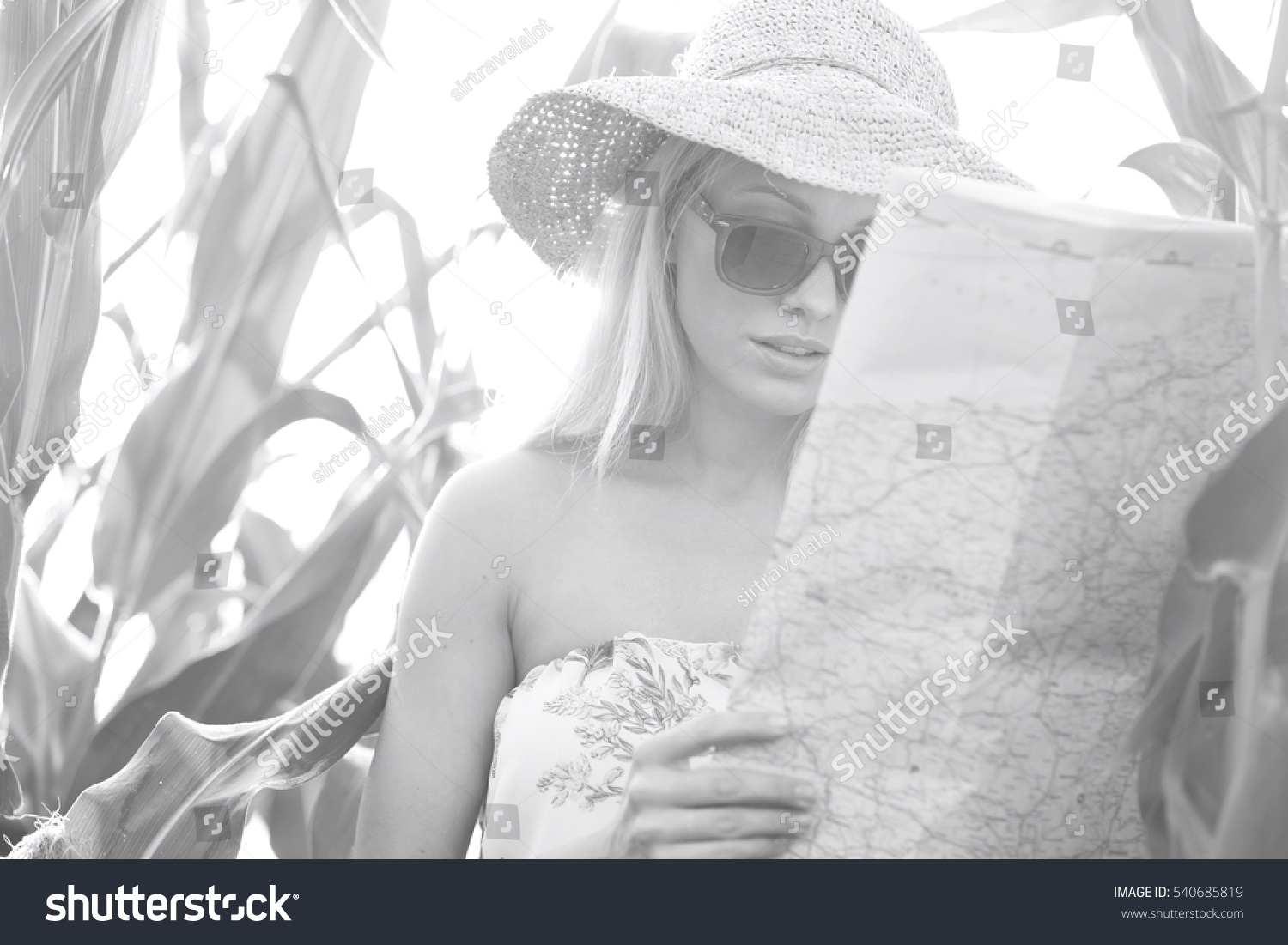 Woman reading map while standing amidst plants outdoors #540685819