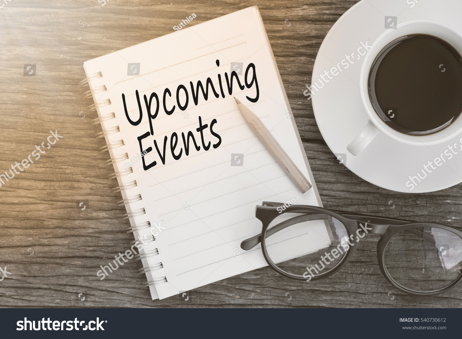 Concept Upcoming Events message on notebook with glasses, pencil and coffee cup on wooden table. #540730612