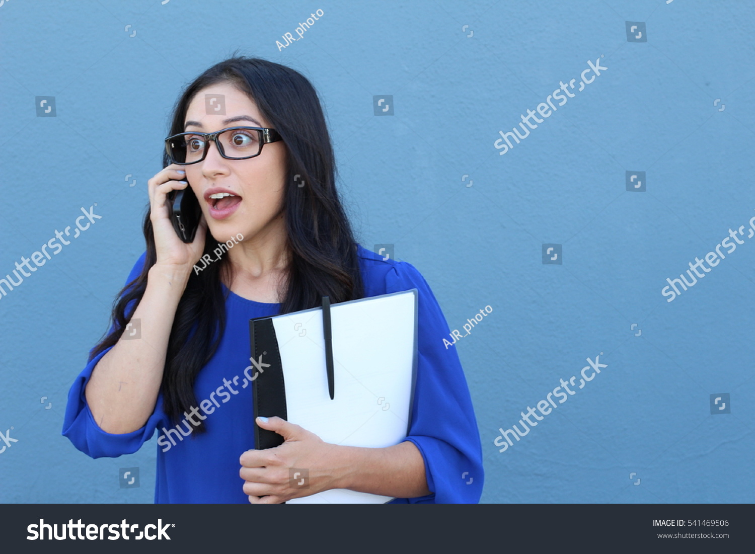 Portrait of a beautiful girl on the phone while getting shocking or surprising news #541469506