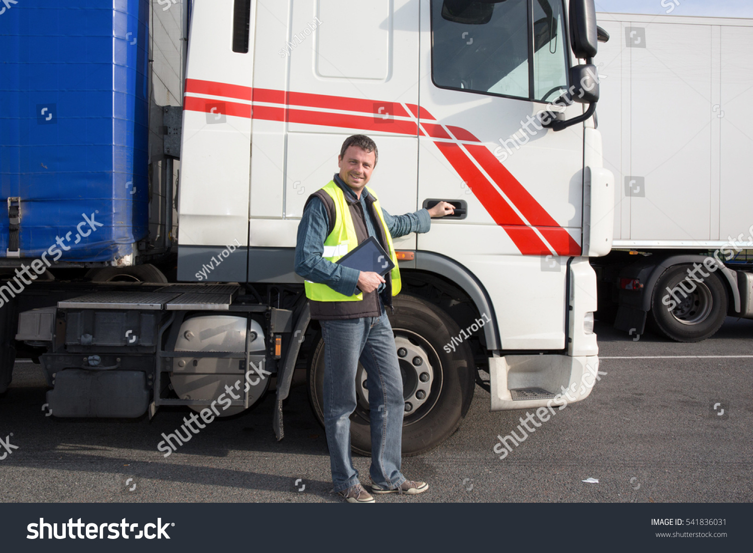 Logistics - proud driver with tablet computer, in front of trucks . #541836031
