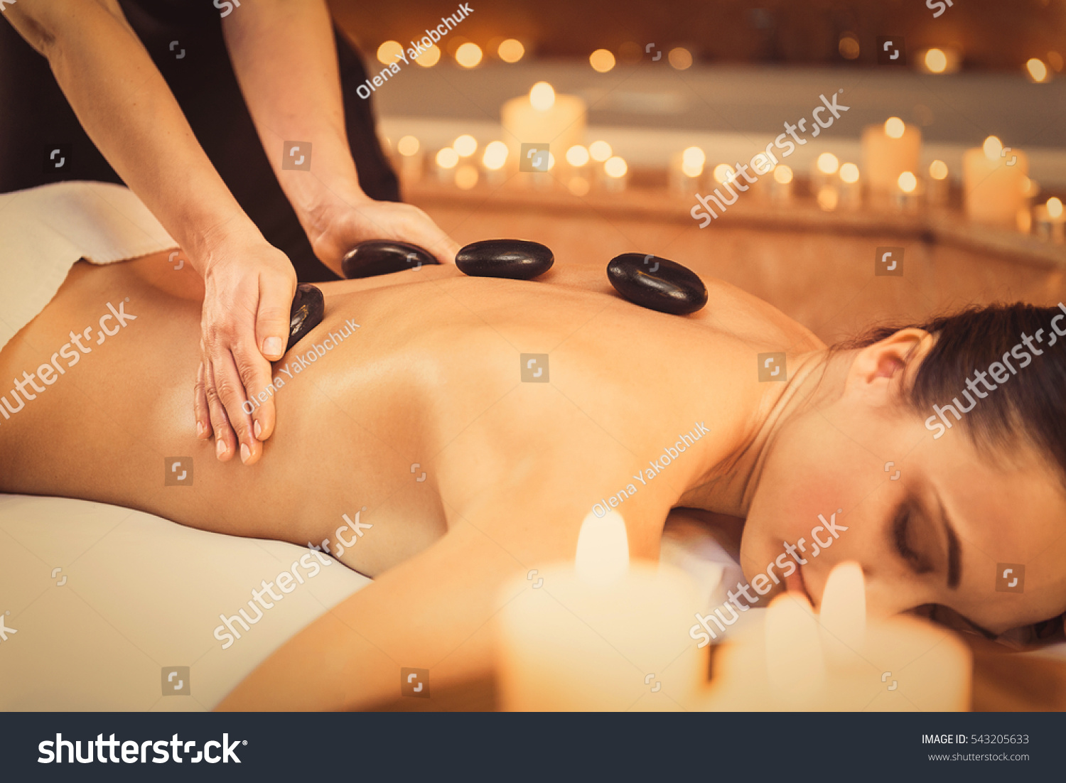 Professional beautician massaging female back by stones #543205633