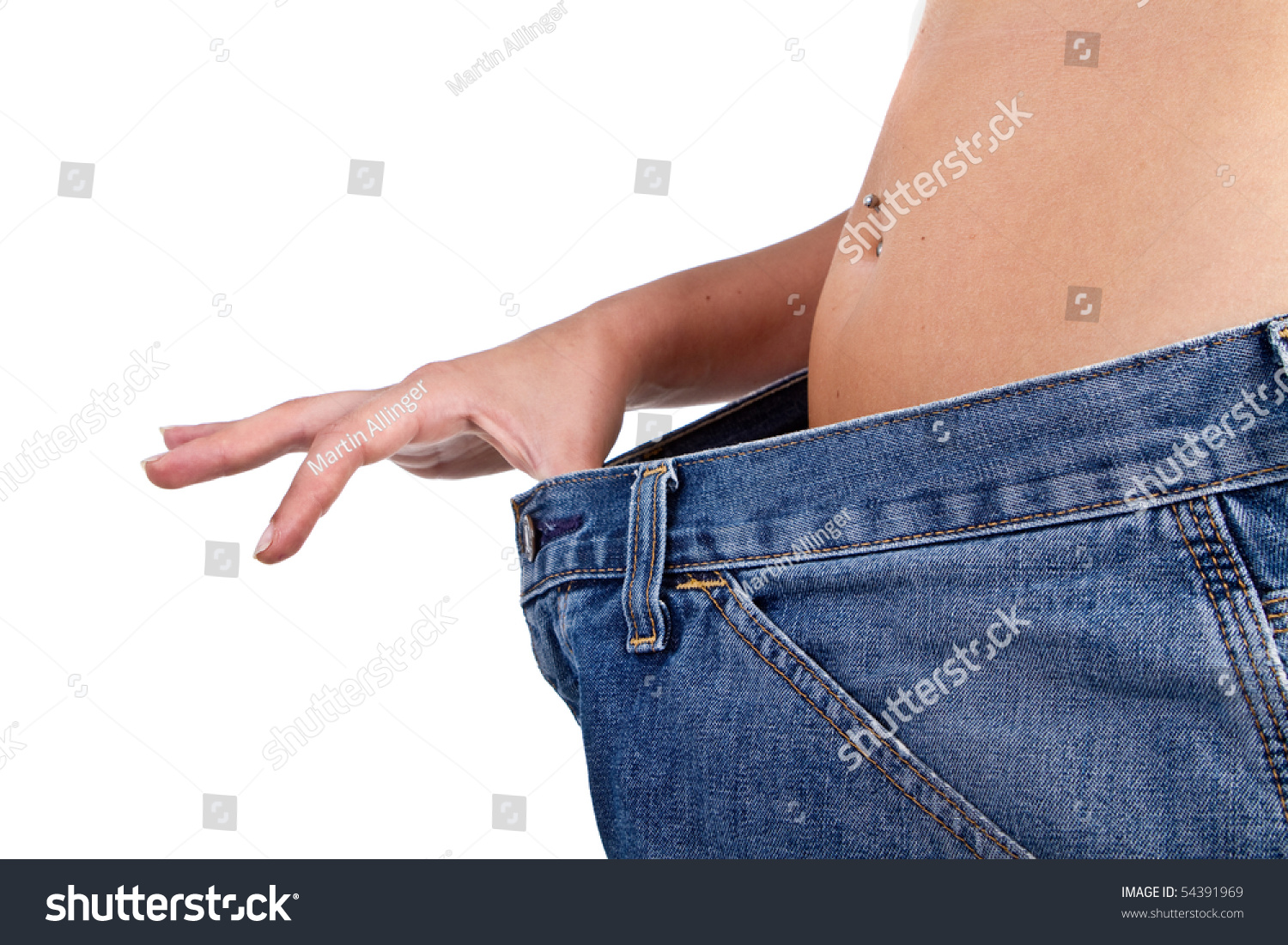 Female Model showing her lost weight by putting on an older jean. #54391969