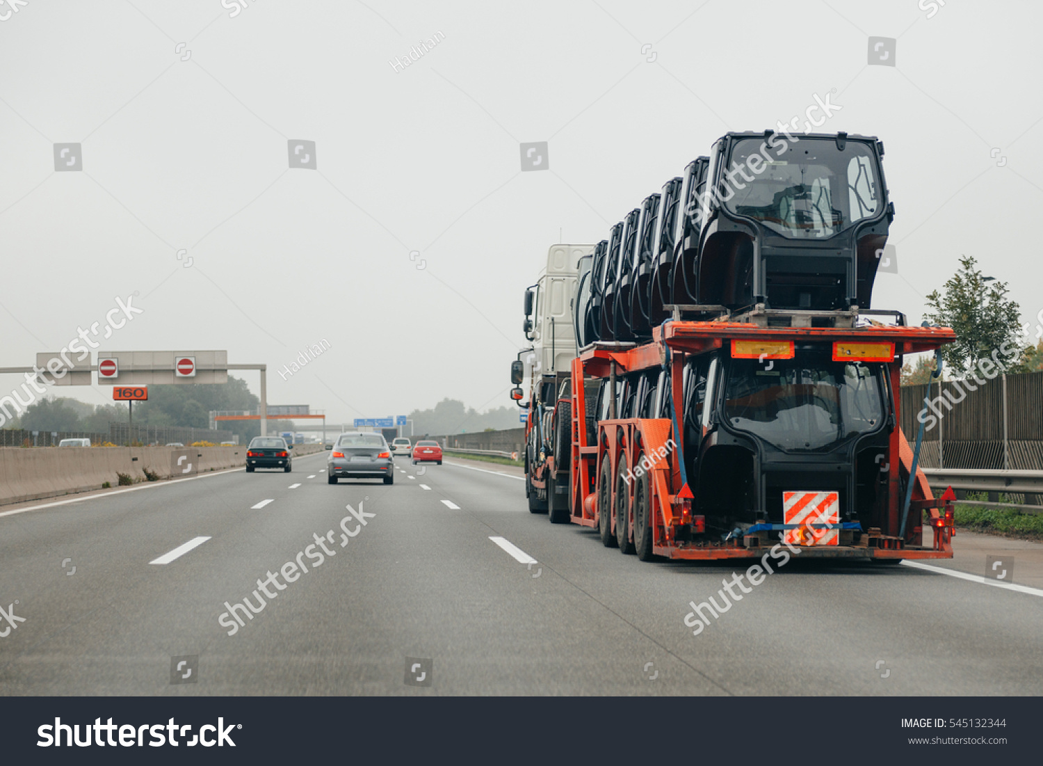 rear view of a big truck with flatbed trailer hauling tractor cabines on german autobahn  #545132344