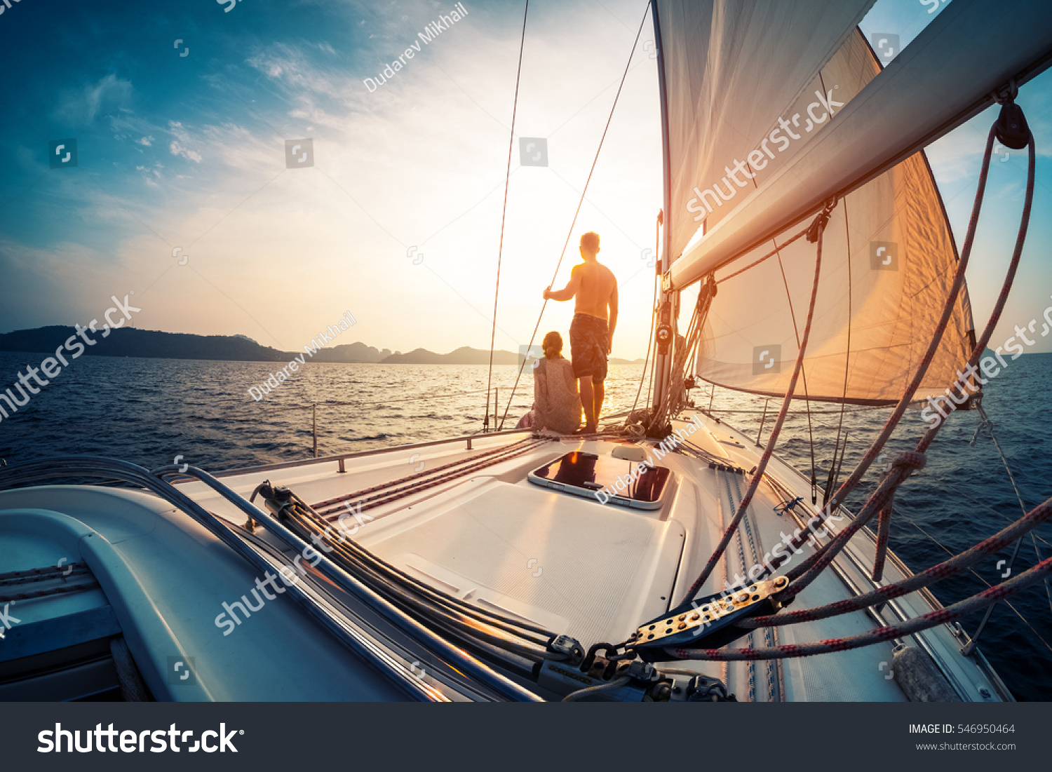 Couple enjoying sunset from the deck of the sailing boat moving in a sea #546950464