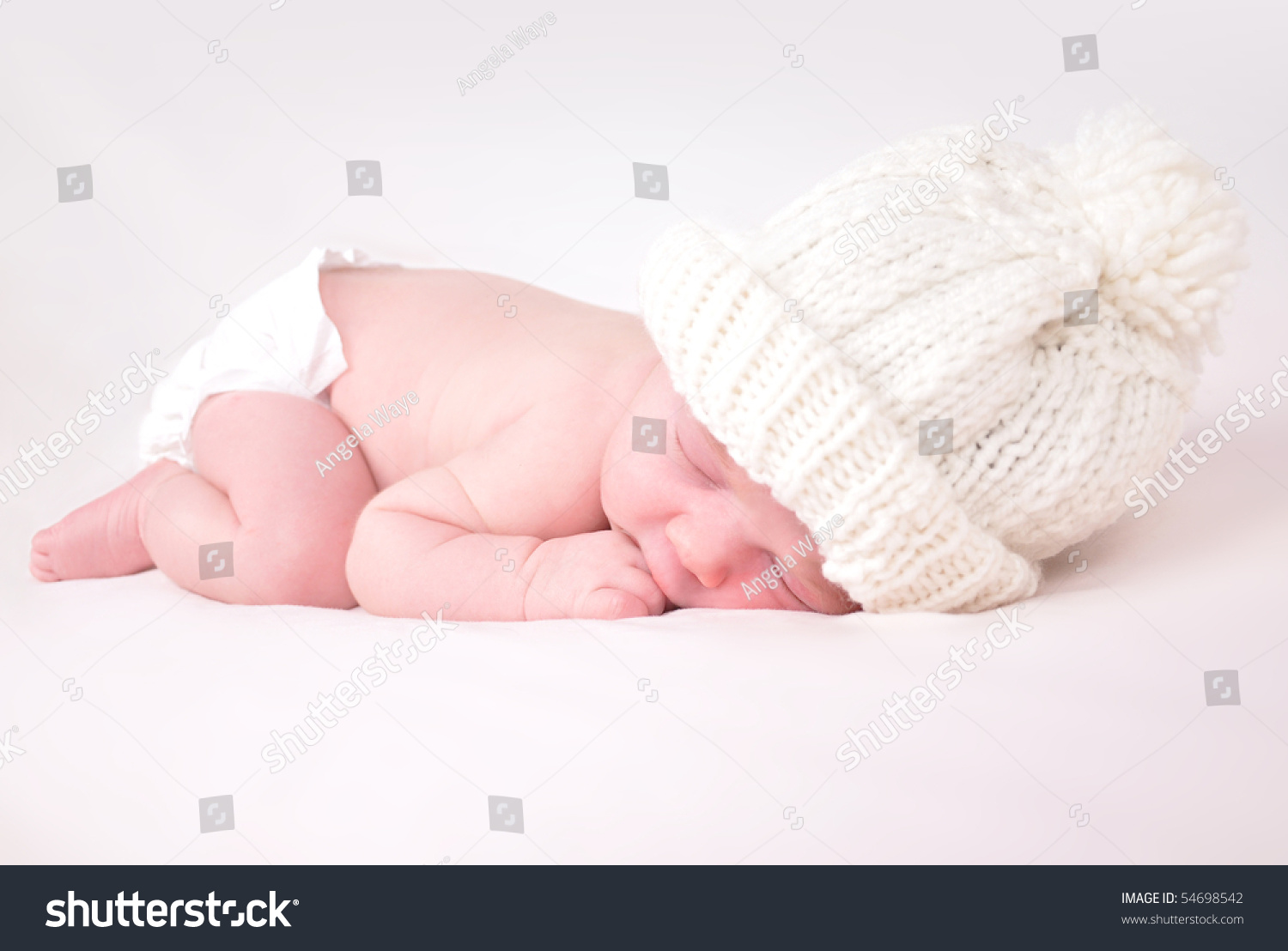 A newborn baby is wearing a white hat and laying down sleeping on a soft white background. Use the photo to represent life, parenting or childhood. #54698542