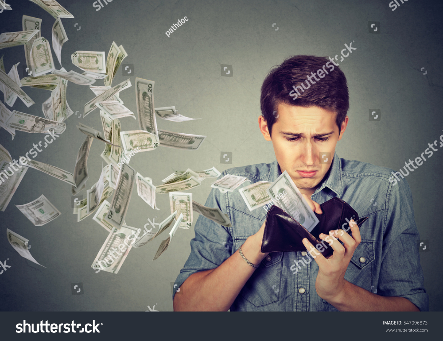 Sad man looking at his wallet with money dollar banknotes flying out away  #547096873