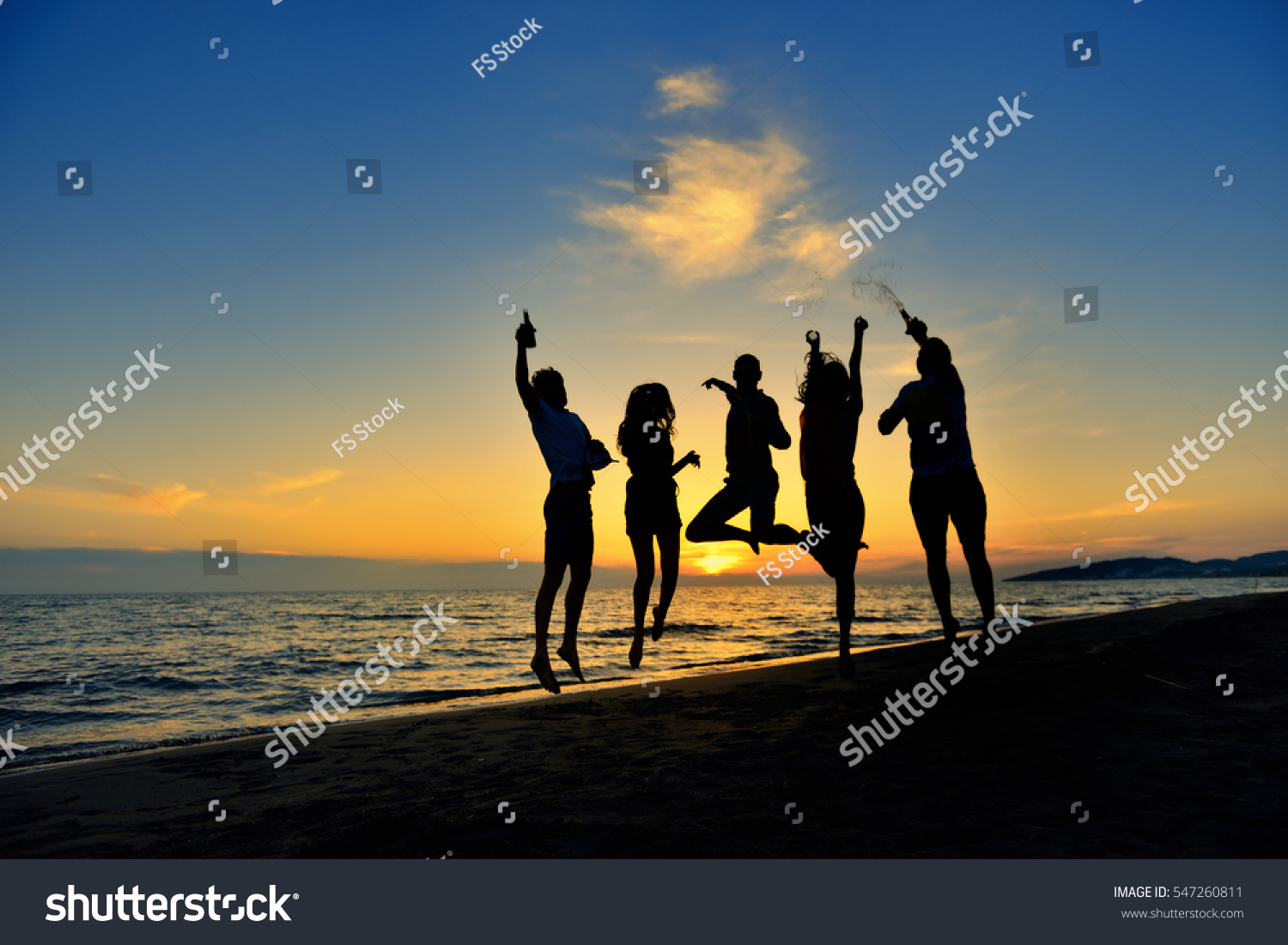 group of happy young people dancing at the beach on beautiful summer sunset #547260811
