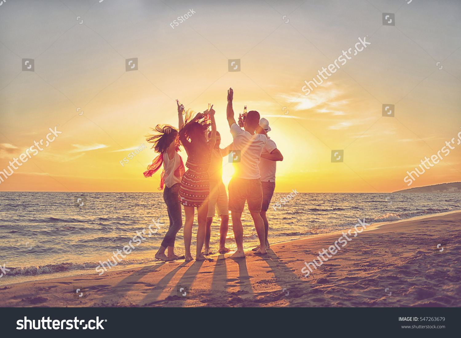 group of happy young people dancing at the beach on beautiful summer sunset #547263679