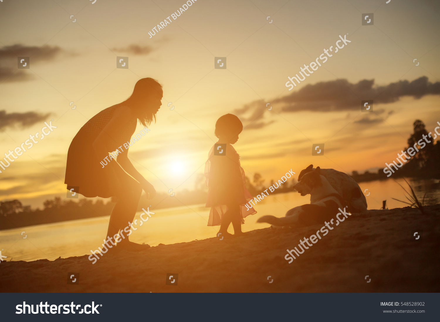 Silhouettes of mother and little daughter walking at sunset #548528902
