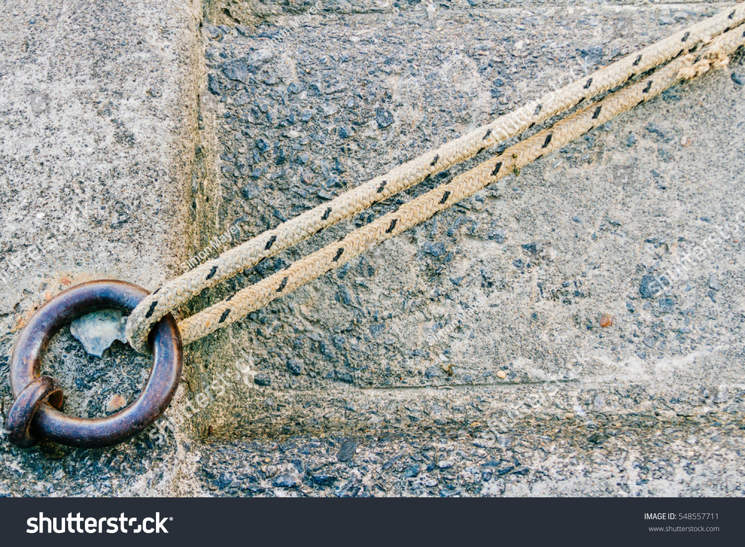 Iron ring with rope tied and concrete background on a dock #548557711