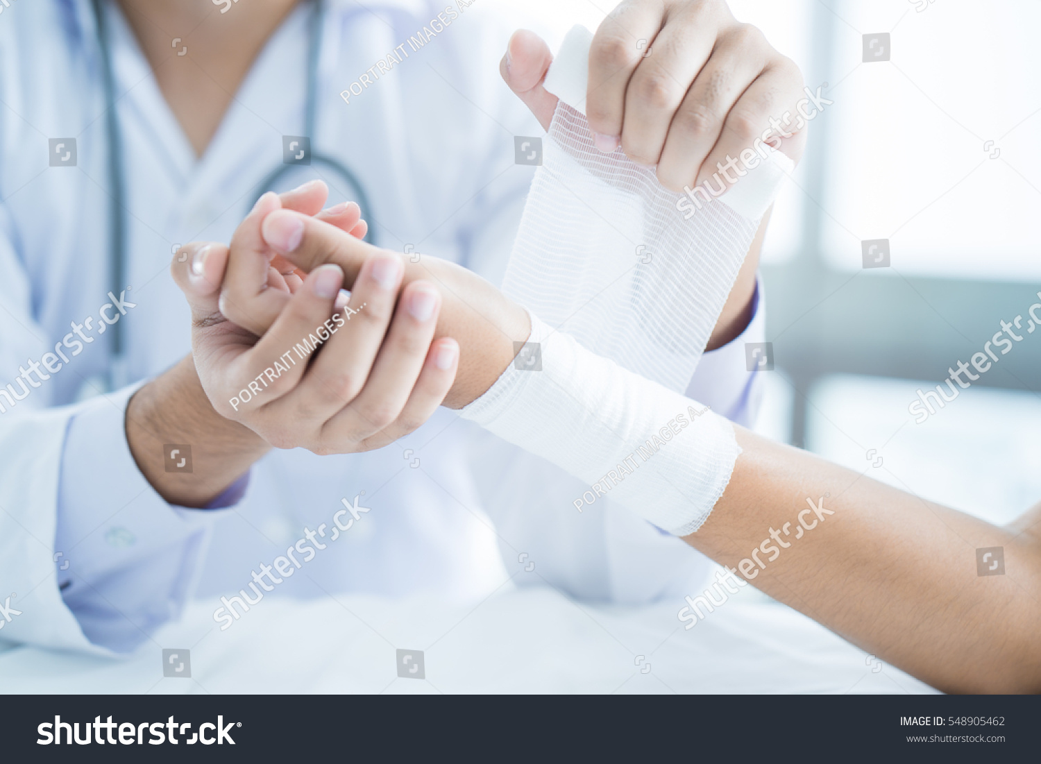 Close-up doctor is bandaging upper limb of patient. #548905462