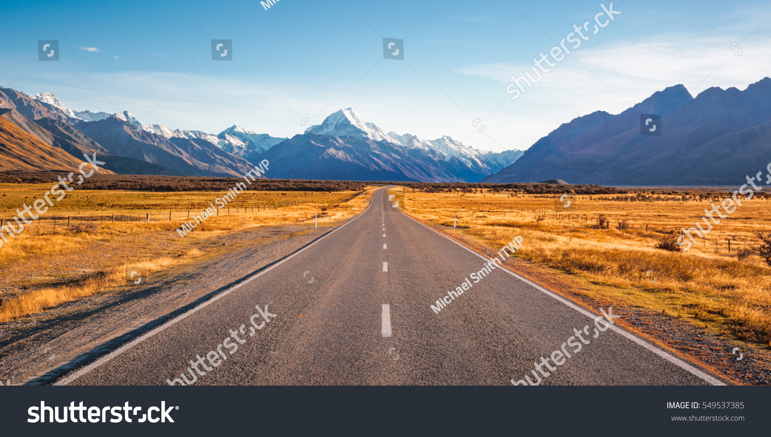 A long straight road leading towards a snow capped mountain in New Zealand #549537385