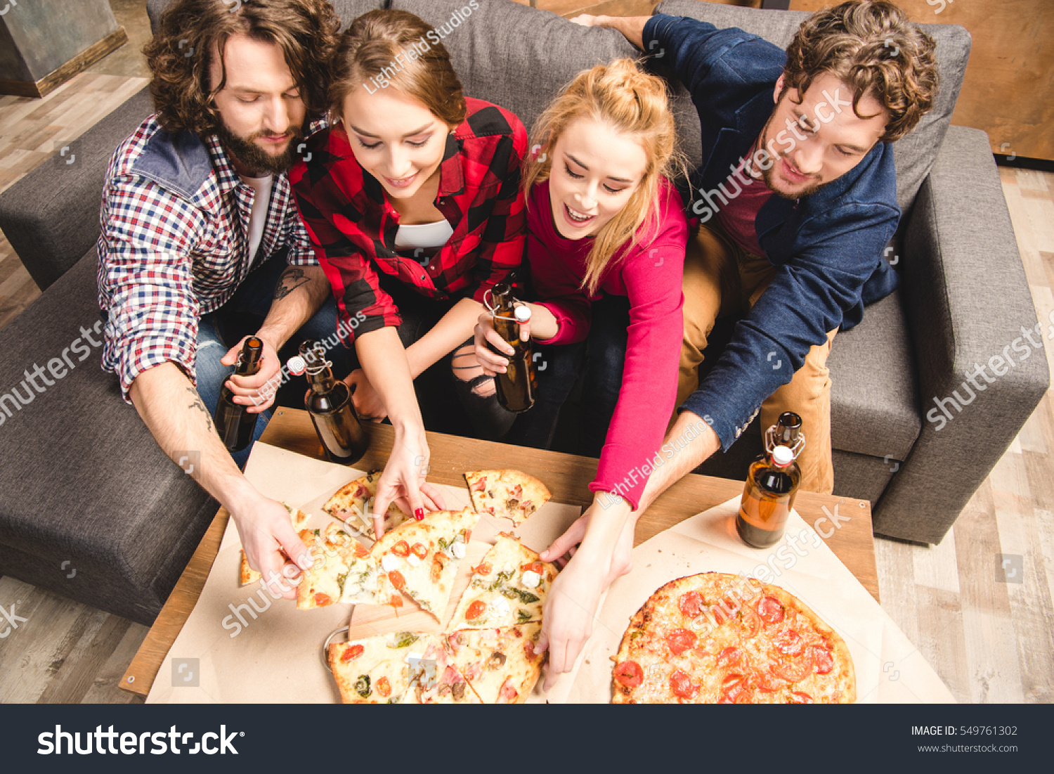 Happy friends enjoying pizza at home party  #549761302