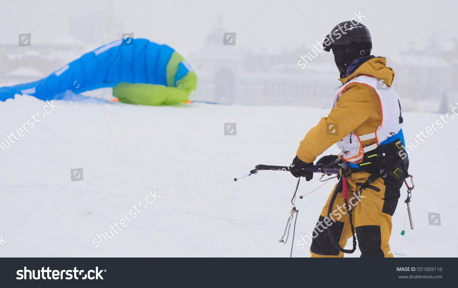 Snowkiting in the snow on frozen river, kite surfer ready for sliding #551069116