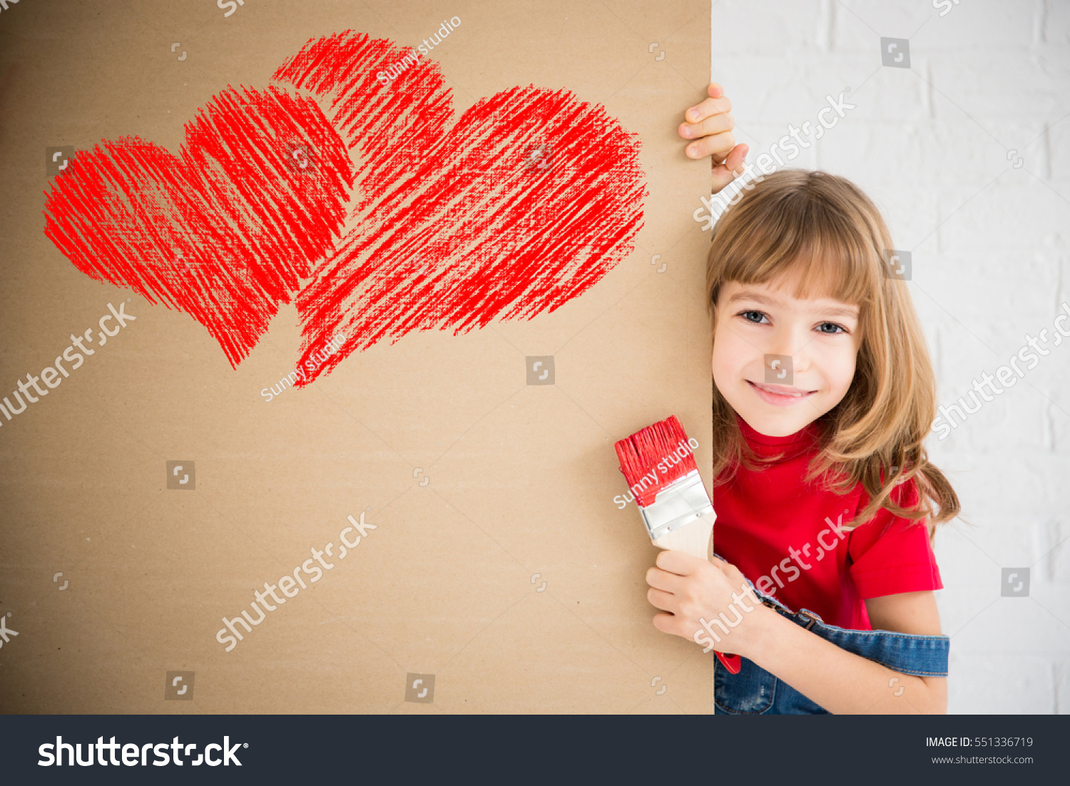 Happy child painting big red heart on the wall. Funny girl playing at home. Valentines day card. Renovation and design concept #551336719