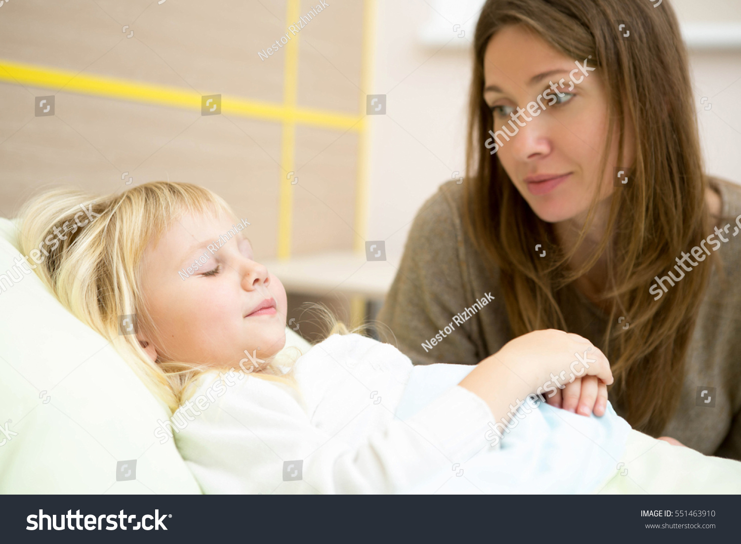 Sleeping well. Beautiful mature woman sitting near her daughterÃ¢??s bed in the hospital ward looking at her sleeping child with love copyspace motherhood children health sleeping illness concept #551463910