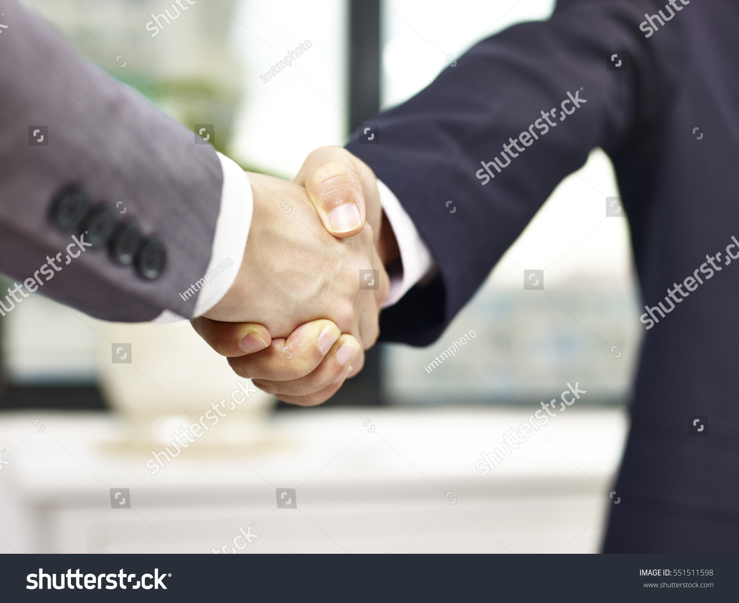 close-up, low angle view of a firm handshake in office by two asian businessmen. #551511598