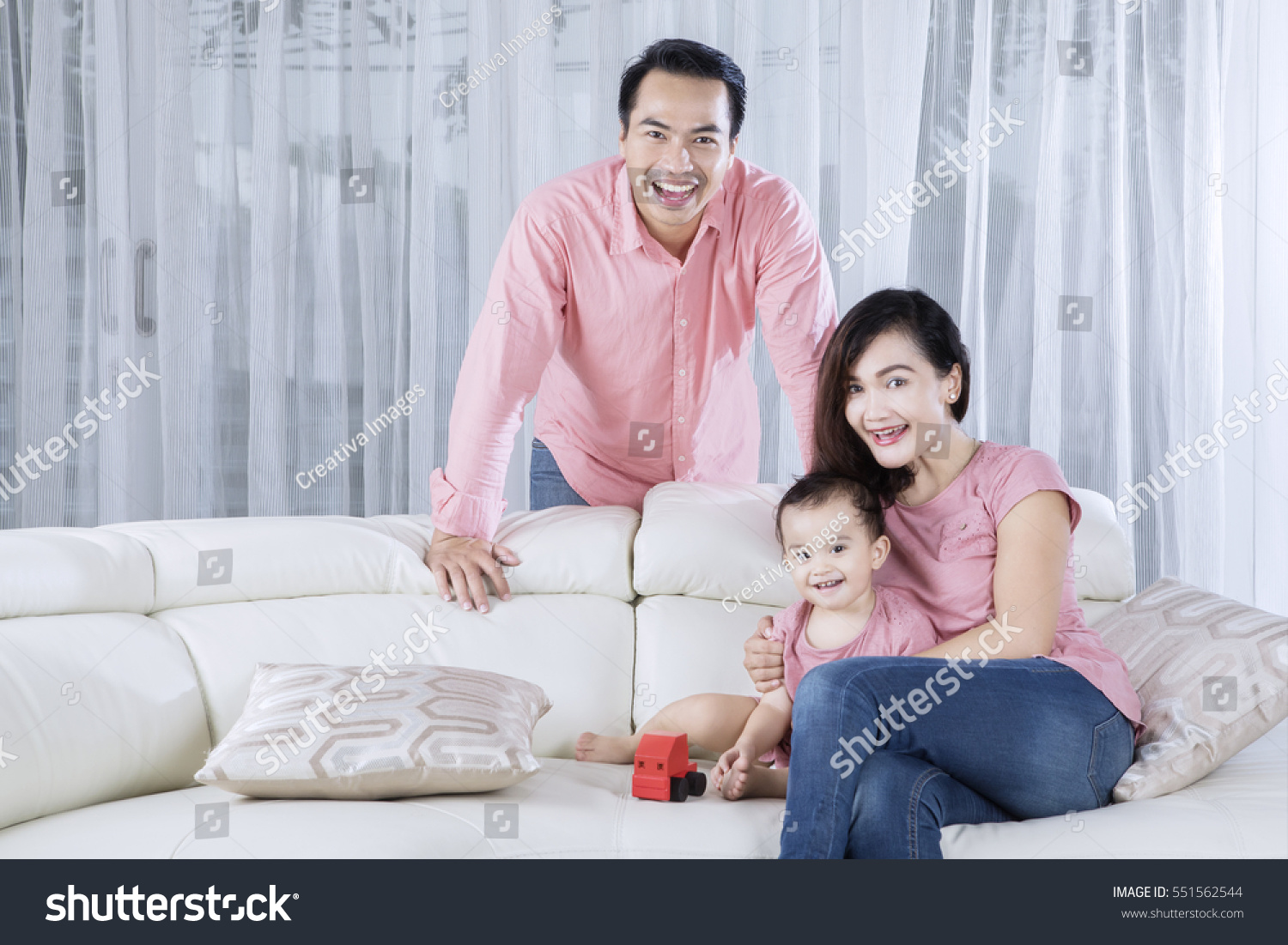 Image of happy family looking at the camera while sitting on the couch  #551562544