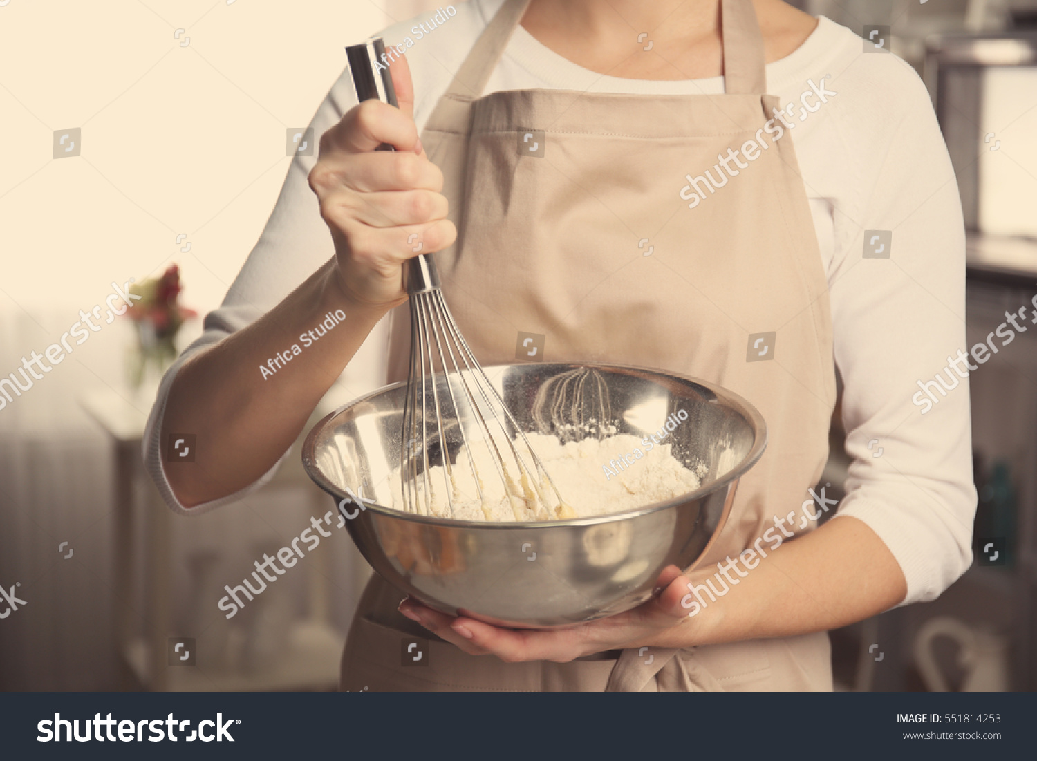 Young woman holding bowl with dough and whisk, closeup #551814253