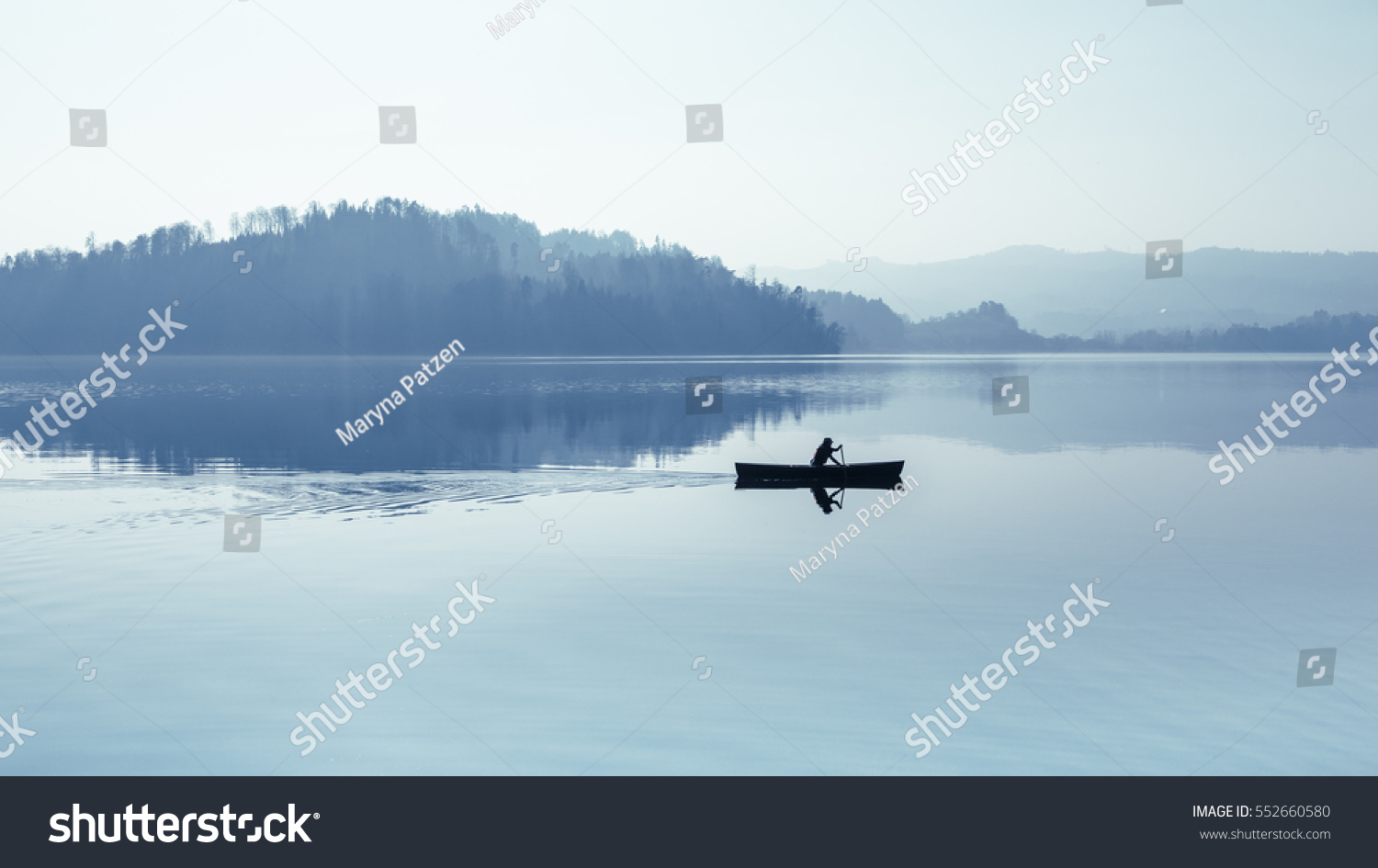 Fog over the lake. In calm water reflection mirror. Man with a paddle in the boat. Black and White. #552660580