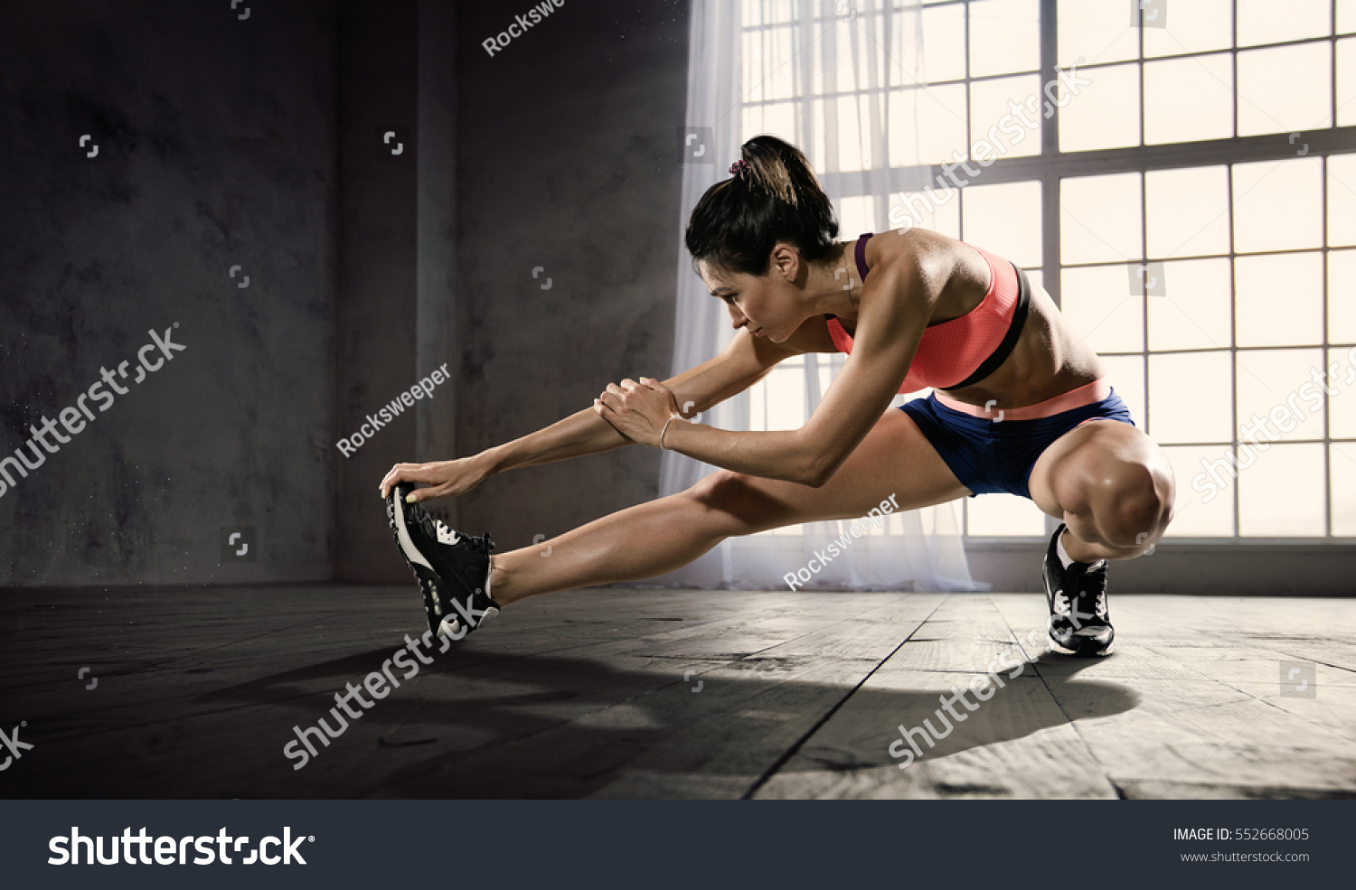 Sports. Woman at the gym doing stretching exercises and smiling on the floor #552668005