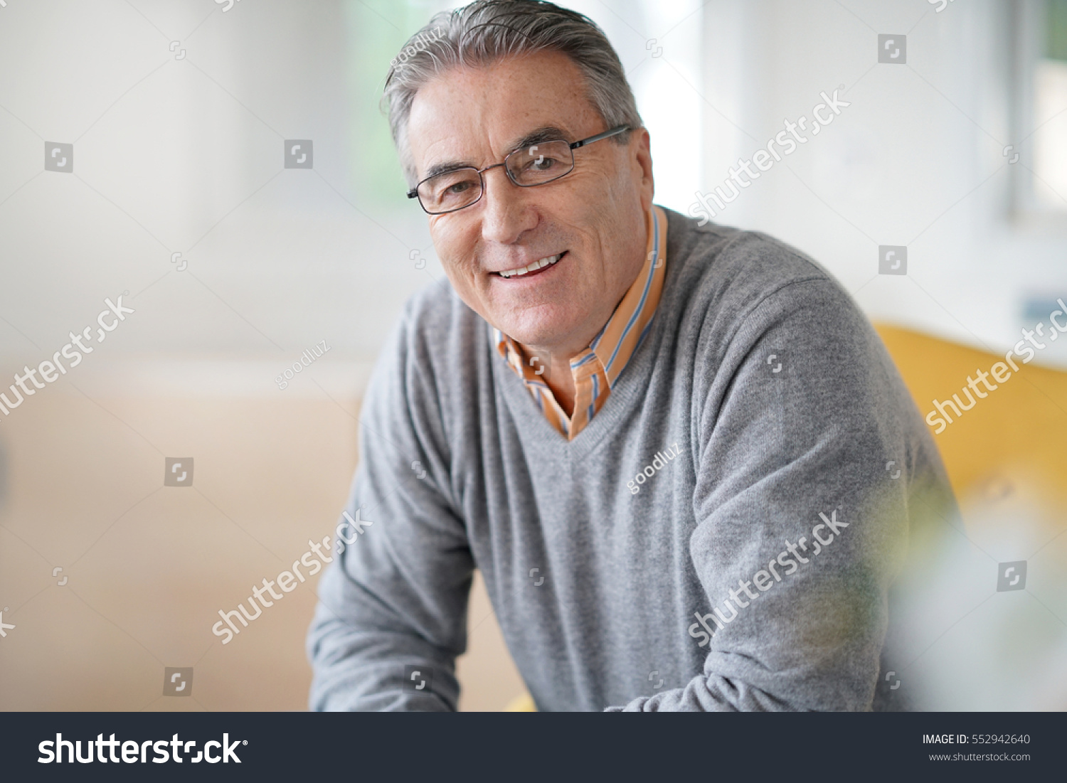 Smiling senior man with eyeglasses relaxing in armchair #552942640