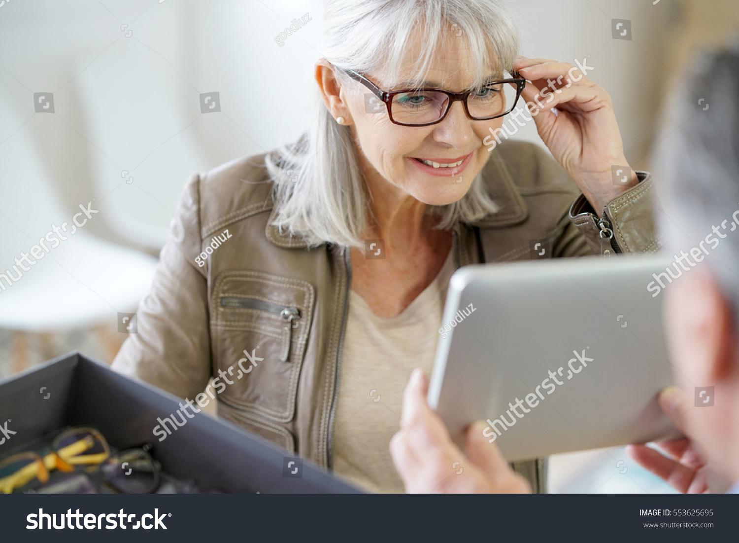 Senior woman in optical store trying eyeglasses on #553625695