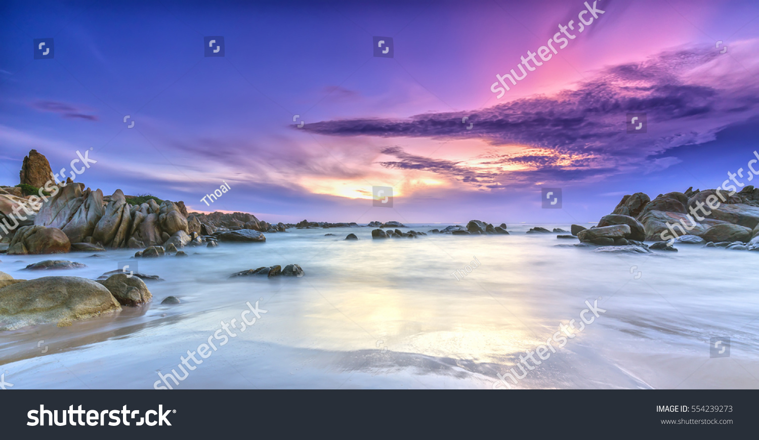 Dawn on the beach with brightly colored clouds, beneath a rock with beautiful shapes create beautiful scenery welcome bright day fresh #554239273