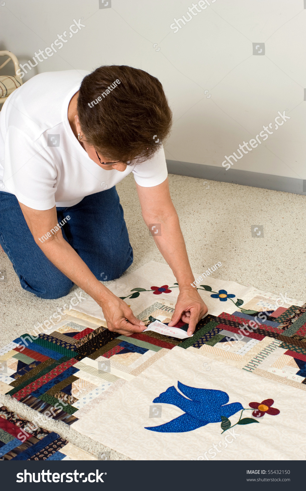 A quilter places a paper label on a panel of fabric prior to quilting. #55432150