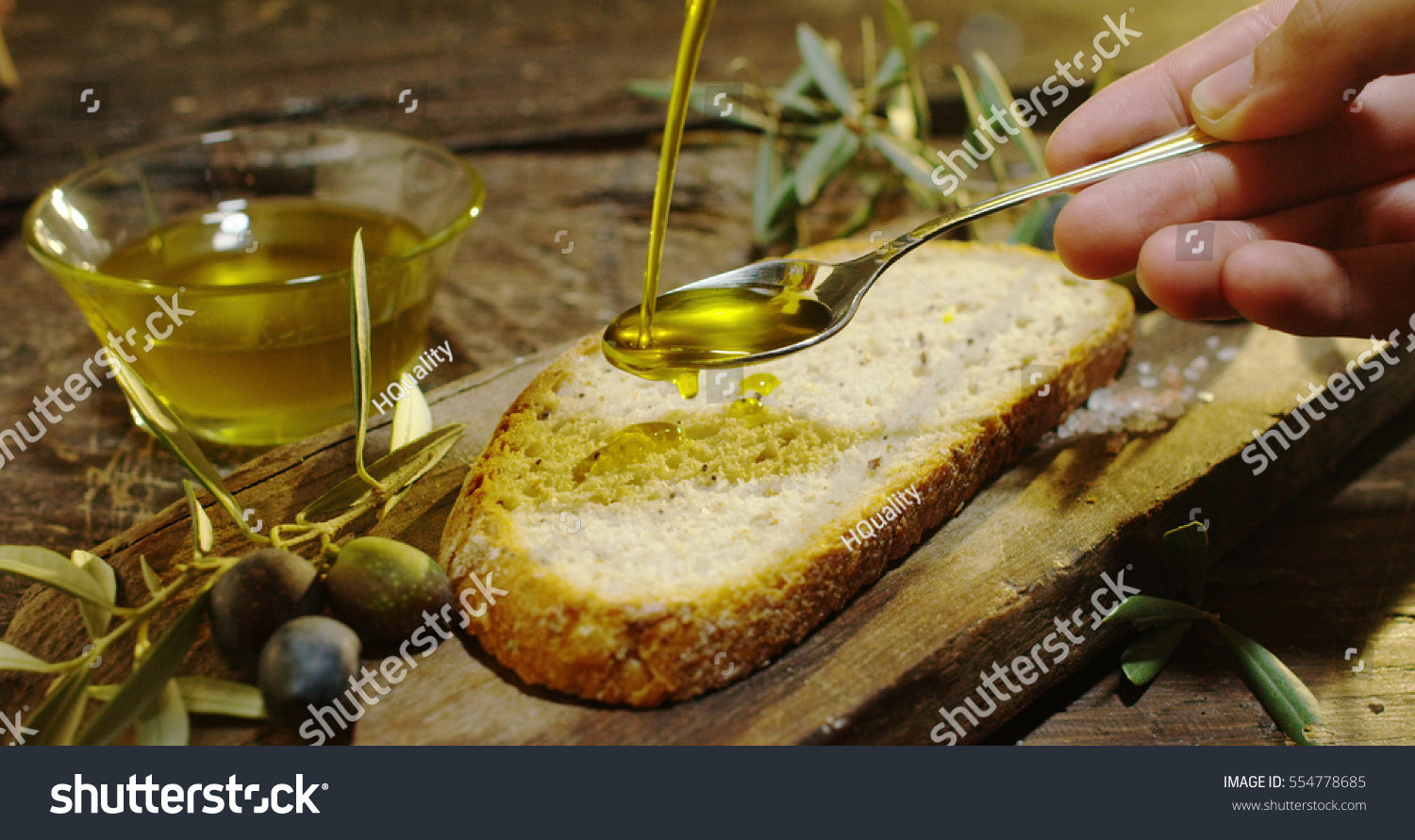 Genuine Italian organic oil cold pressed in slow motion falls on organic bread. concept of nature and healthy food, healthy and natural. fresh olives and Tuscan Italian oil #554778685