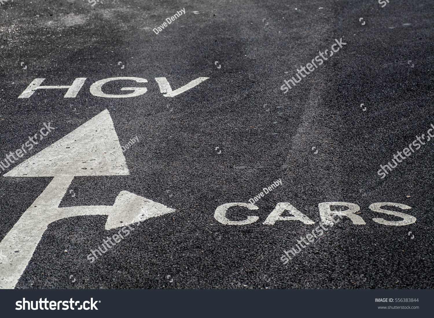 White painted arrow on the tarmac directs cars and trucks to different areas #556383844