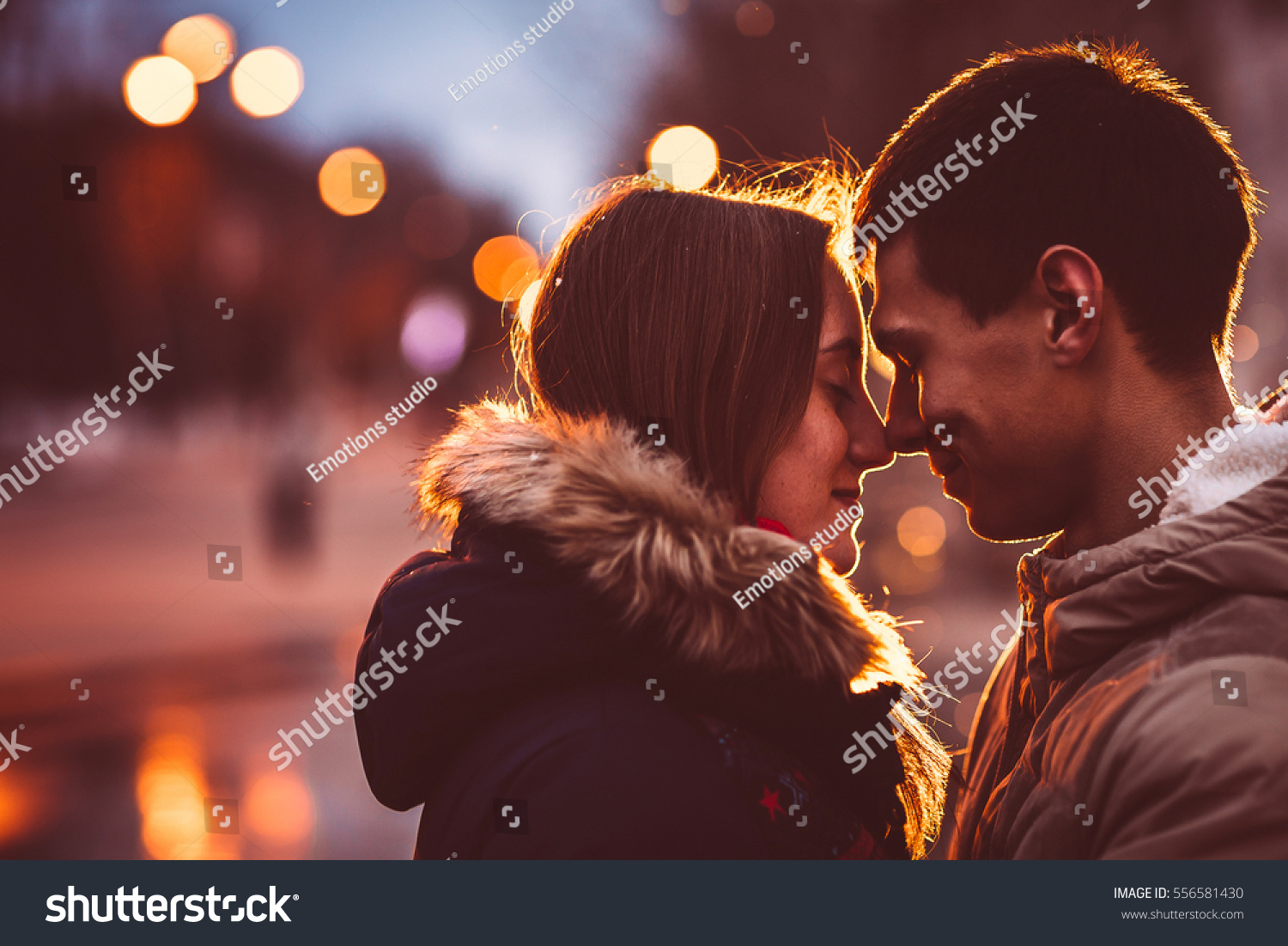 Portrait of young beautiful couple kissing in an autumn rainy day. Filtered with grain and light flashing #556581430