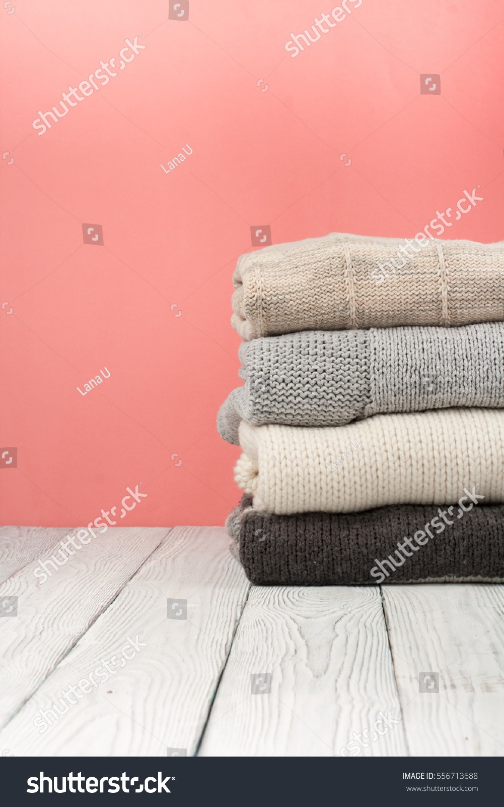 Knitted wool sweaters. Pile of knitted winter clothes on blue wooden background, sweaters, knitwear, space for text. #556713688