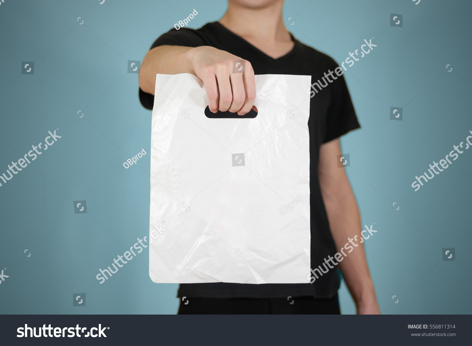 Man shows white blank plastic bag mock up isolated. Empty white polyethylene package mockup. Consumer pack ready for logo design or identity presentation. Commercial product food packet handle #556811314