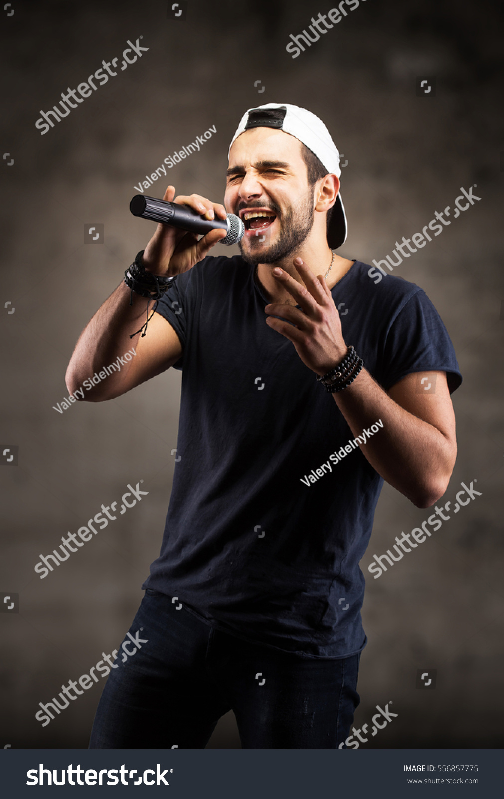 Studio portrait of a handsome young man singing to the microphone #556857775