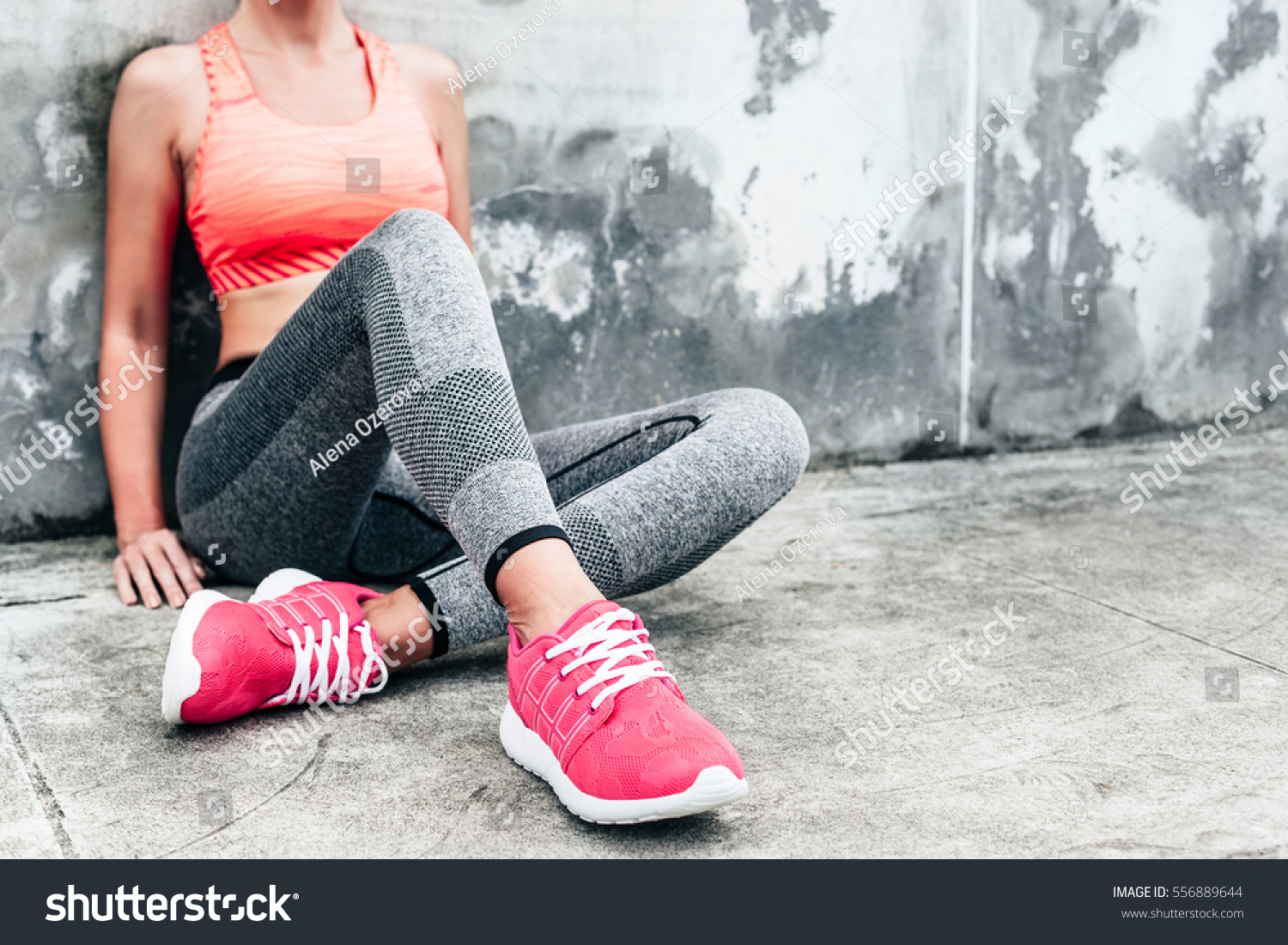 Fitness sport woman in fashion sportswear doing yoga fitness exercise in the city street over gray concrete background. Outdoor sports clothing and shoes, urban style. Sneakers closeup. #556889644